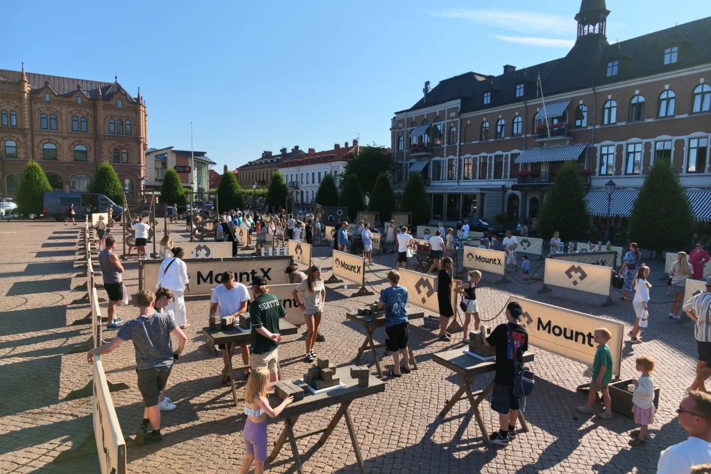 Familjer som provar MountX-stationer på ett stenlagt torg mitt i staden
